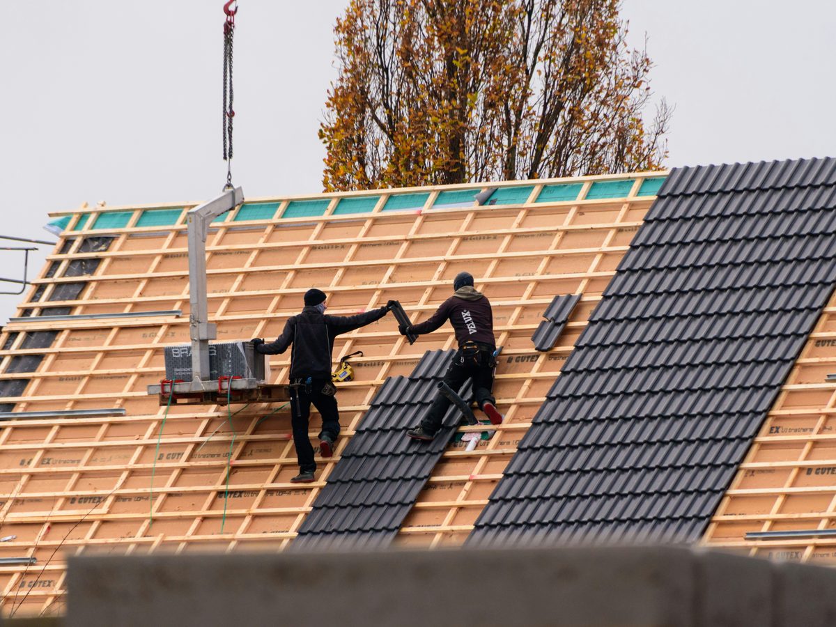 Roofers installing tiled roofing on a home construction project